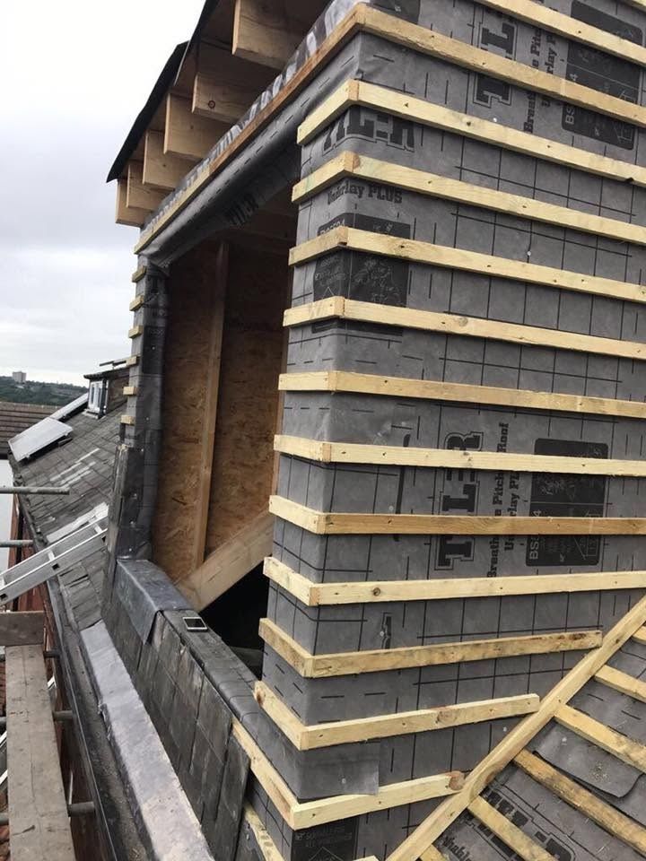 Dormer under construction with cheeks wrapped in breathable membrane and battens, above an existing slate roof