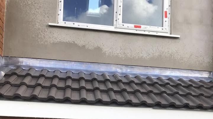Charcoal double roman tiles and new lead apron flashing over an extension, with timber studwork and blockwork visible in the opening below