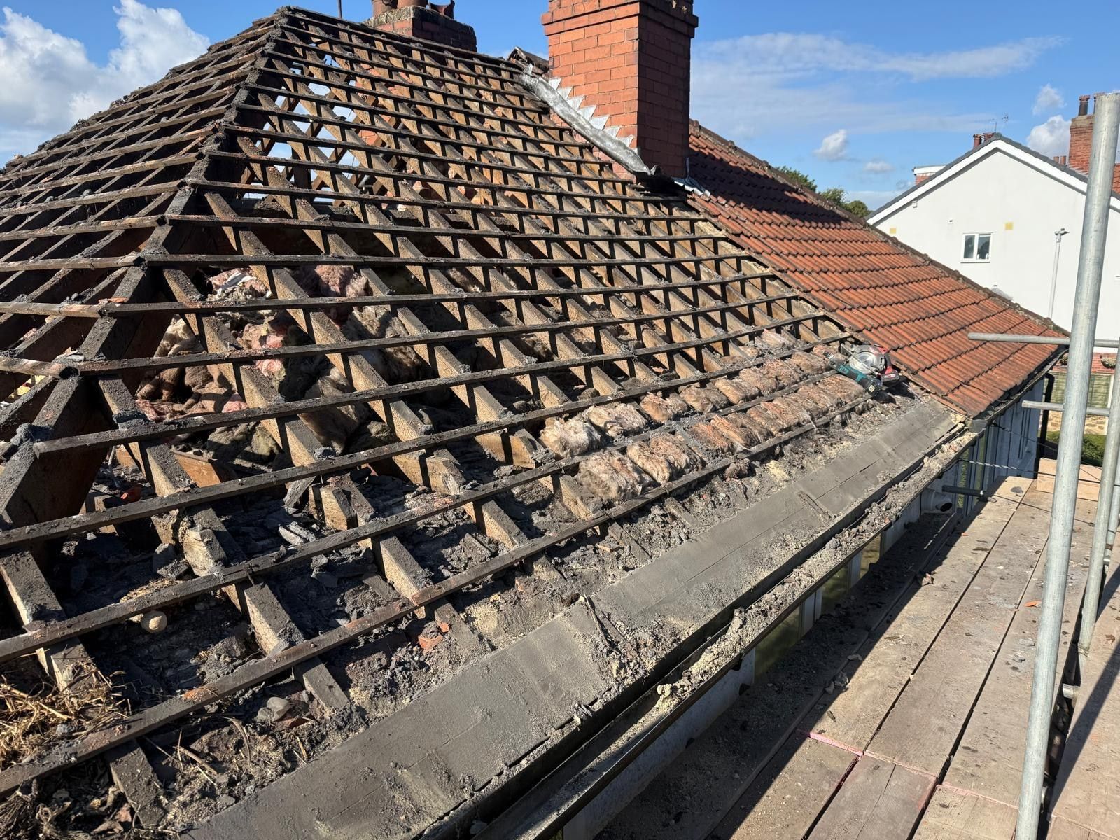 Hipped roof stripped back to rafters with a brick chimney prepared with new lead soakers, neighbouring pantile roofs beyond