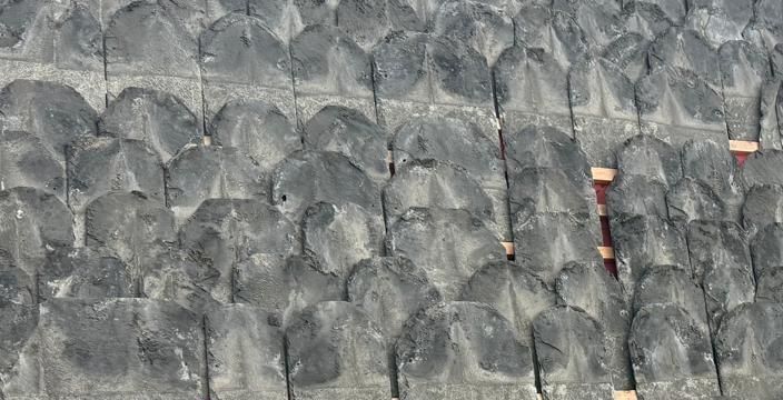 Close texture of heavy random stone slates hung in diminishing courses over red membrane
