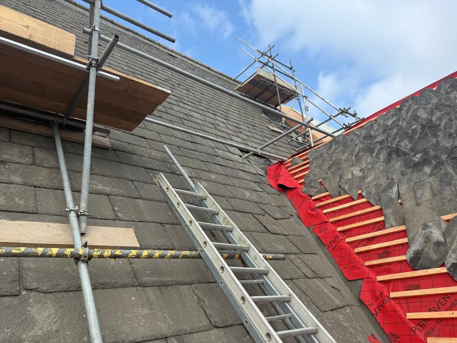 Heritage roof slope part way through re-slating, old stone slates on one side and new battens with slates being laid on the other